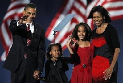 Barack, Sasha, Malia, and Michelle Obama smile and wave to the huge crowd gathered for a late night victory celebration. Photo taken in Hyde Park, Chicago, on November 4, 2008