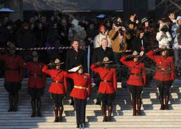 Officers of the Royal Canadian Mounted Police (RCMP) salute the President as his motorcade passes by the Canadian Embassy. Canadian Ambassador Michael Wilson (right) and Canadian Foreign Affairs Minister Peter Kent (left) stand behind the RCMP officers.