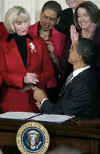President Barack Obama signs his first bill into law as president in the East Room of the White House on January 29, 2009. President Obama signs the Lilly Ledbetter Fair Pay Act designed to eliminate pay inequities based on sex discrimination. Members of Congress. Hillary Clinton, and others join in witnessing the historic moment of Obama's signing of his first bill.