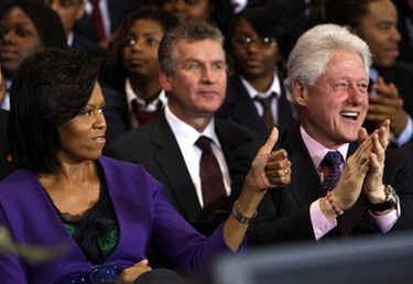 First Lady Micelle Obama sits next to Bill Clinton at the signing ceremony at the inner city Washington, DC school on April 21, 2009.