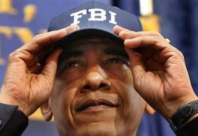 President Obama is introduced by FBI Director Robert Mueller who gives Obama an FBI cap.