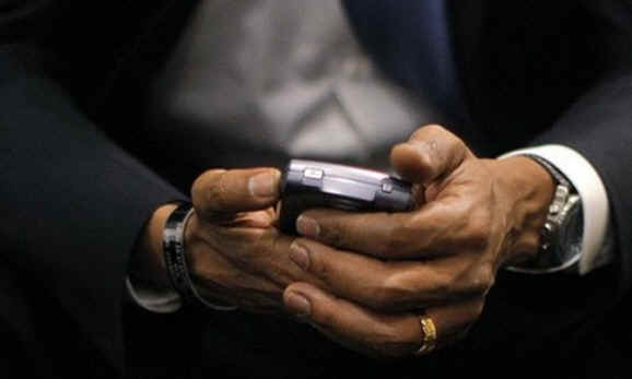 President Barack Obama with his Blackberry device between his hands.