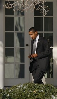President Barack Obama uses his secure Blackberry then holsters the device on January 29, 2009 as he walks in the morning sun to the Oval Office.