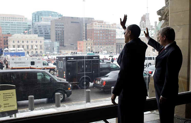 Behind protective glass, Obama and Harper wave to thousands of Obama supporters after arriving at the Parliament building. President Obama meets Canadian Prime Minister Stephen Harper on Parliament Hill in Ottawa on February 19, 2009.