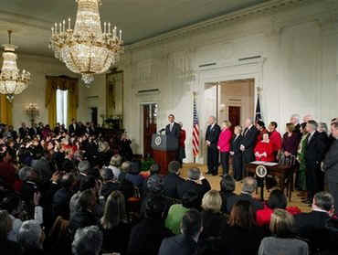 President Barack Obama signs his first bill into law as president in the East Room of the White House on January 29, 2009. President Obama signs the Lilly Ledbetter Fair Pay Act designed to eliminate pay inequities based on sex discrimination. Members of Congress. Hillary Clinton, and others join in witnessing the historic moment of Obama's signing of his first bill.