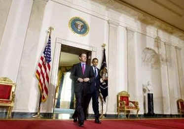 President Barack Obama leaves the Blue Room of the White House and speaks in the Grand Foyer with Treasury Secretary Timothy Geithner. Obama advises that any financial institution that requires a bailout will cap executive salaries at $500,000 per year.