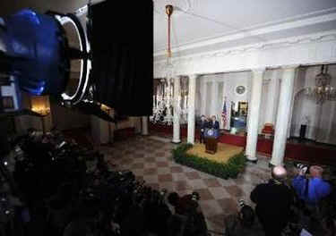 President Barack Obama leaves the Blue Room of the White House and speaks in the Grand Foyer with Treasury Secretary Timothy Geithner. Obama advises that any financial institution that requires a bailout will cap executive salaries at $500,000 per year.
