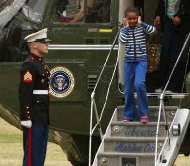 Sasha Obama departs Marine One covering her ears from the loud noise of the helicopter and runs across the South Lawn to the White House residence.